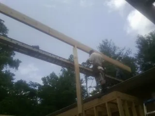 Carpenter setting a ridge beam over a new addition frame — Ice Dam Removal by Roofing Brothers in Britt