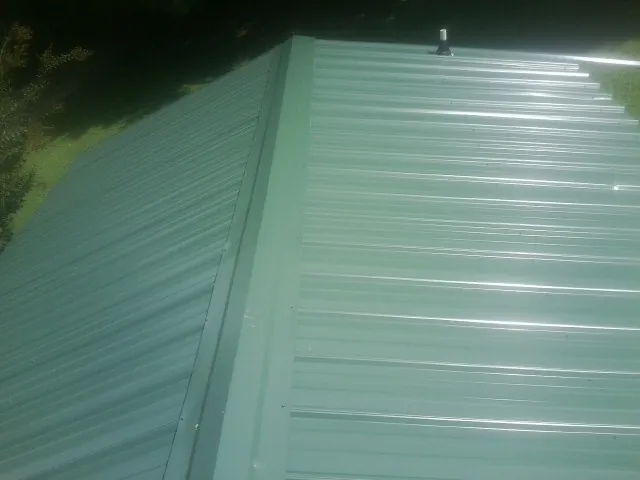 New green metal panels meeting at the ridge of a roof — Flat Roof Repair work by our crew in Britt