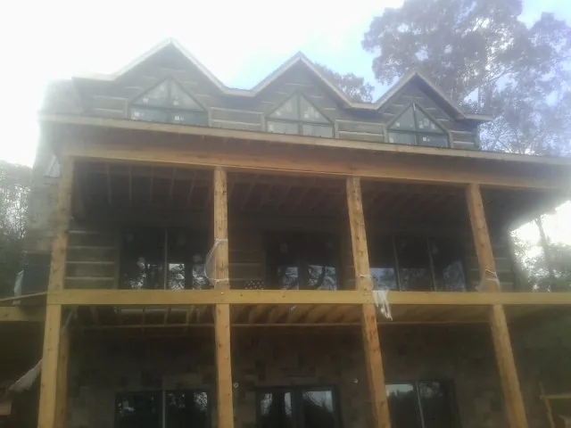 Dormers and porch framing on a large log home under construction — Roof Coating work by our crew in Britt