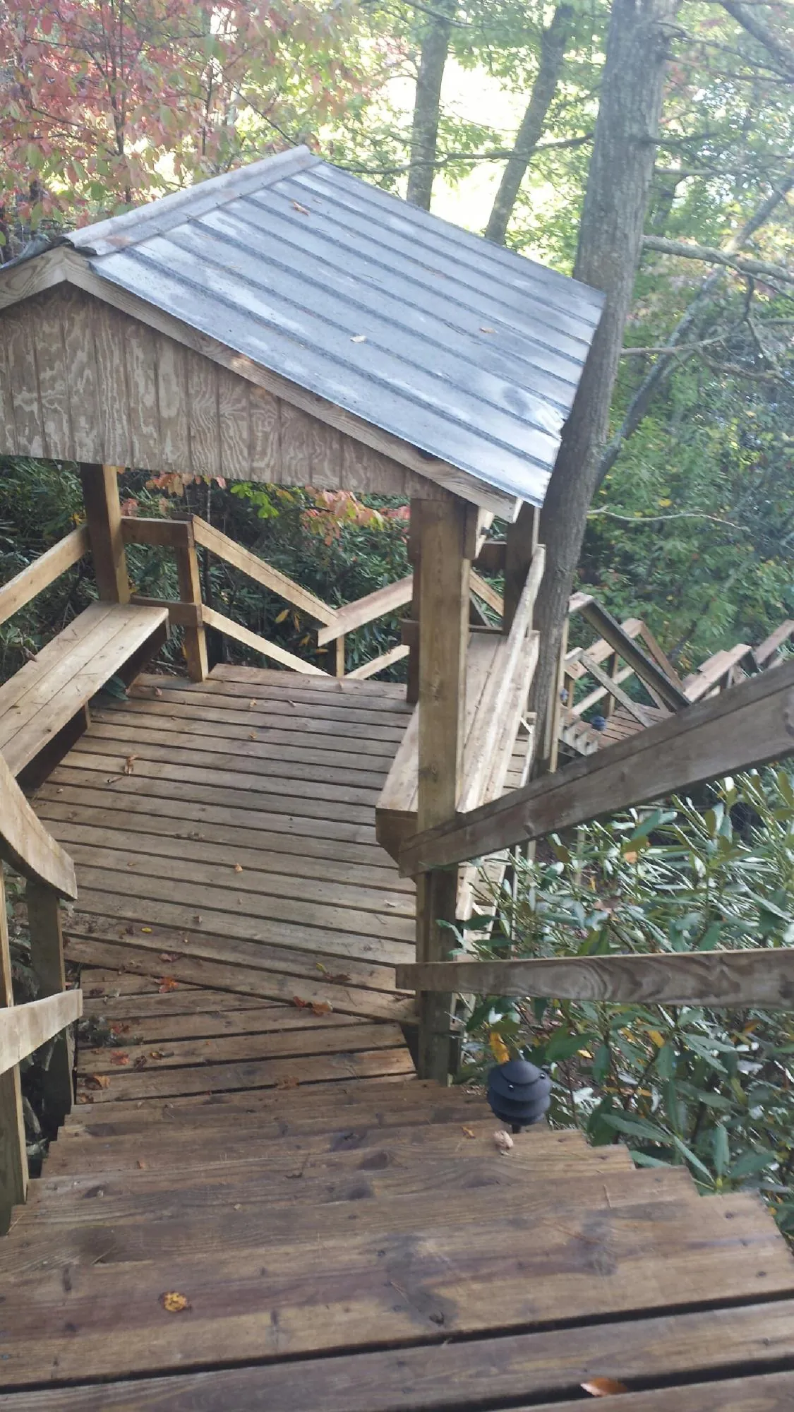Metal roofed shelter over wooden steps on a wooded walkway — Skylight Repair & Installation work by our crew in Britt