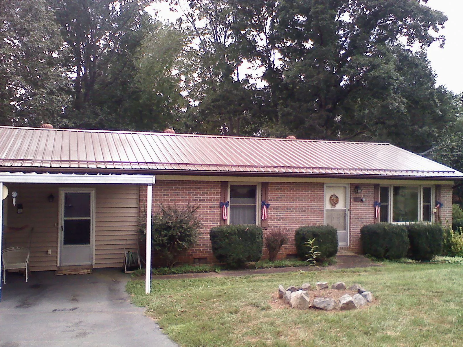 Bronze metal roof and carport on a brick ranch home — Roof Repair work by our crew in Britt
